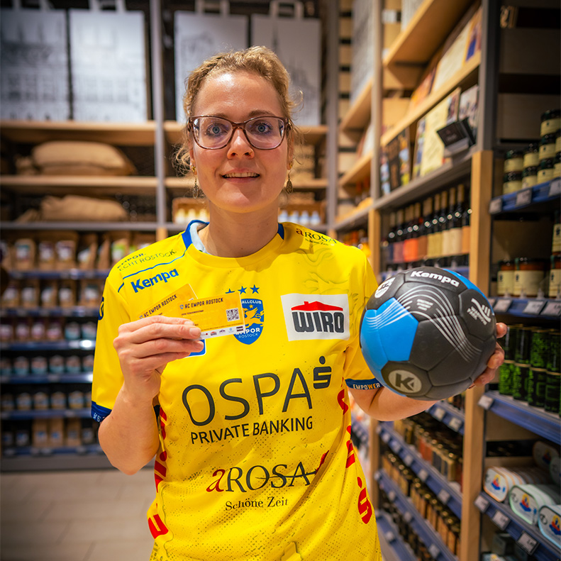 Ein Mitarbeiterin des E center Warnow Parks präsentiert die Dauerkarten des HC Empor Rostock.