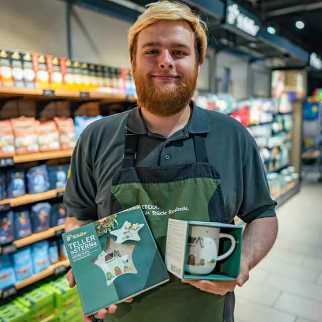 Mitarbeiter des E center Warnow Parks zeigt Tchibo Artikel.