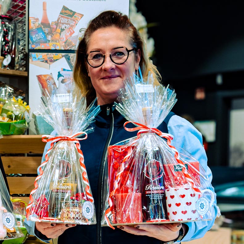 Mitarbeiterinnen des E center Warnow Parks präsentieren Geschenkkörbe zum Valentinstag.