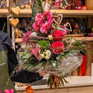 Mitarbeiterin aus dem E center Warnow Park präsentiert Blumenstrauß und Geschenkkorb