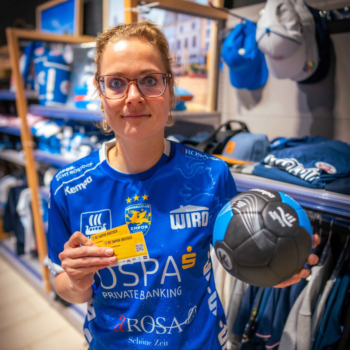 Ein Mitarbeiterin des E center Warnow Parks präsentiert die Dauerkarten des HC Empor Rostock.