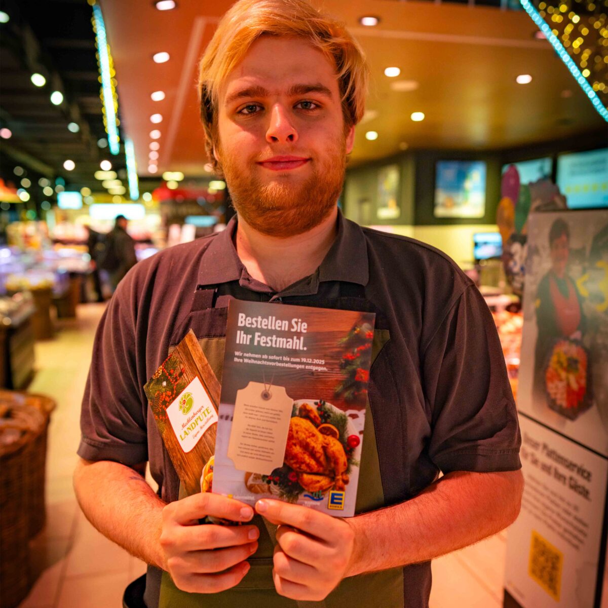 Mitarbeiter aus dem E center Warnow Park präsentiert den Flyer für Weihnachtsvorbestellungen