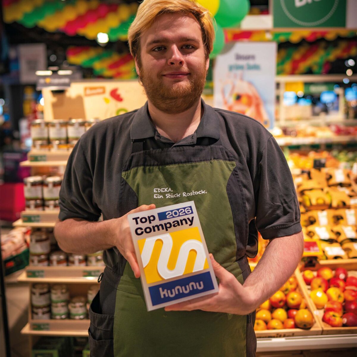 Mitarbeiter aus dem E center Warnow Park präsentiert das kununu Top Company 2026 Siegel.