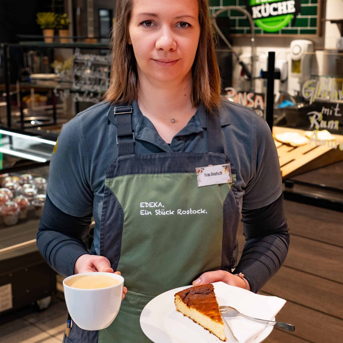 Mitarbeiterin der Marktküche präsentiert Kaffee und hausgemachten Kuchen