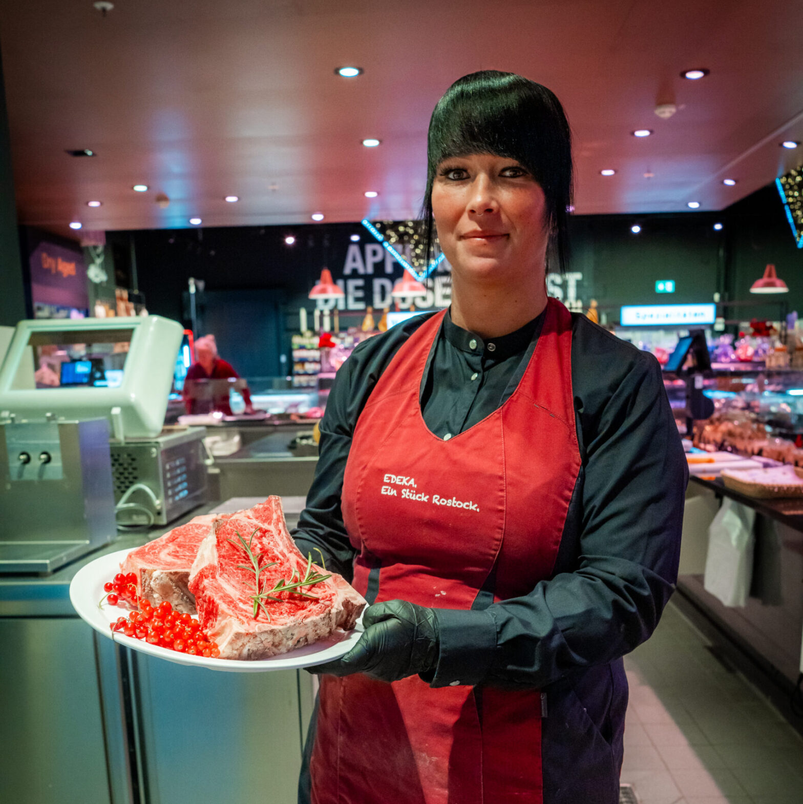 Mitarbeiterin aus dem E center Warnow Park präsentiert Fleisch aus der Bedientheke.
